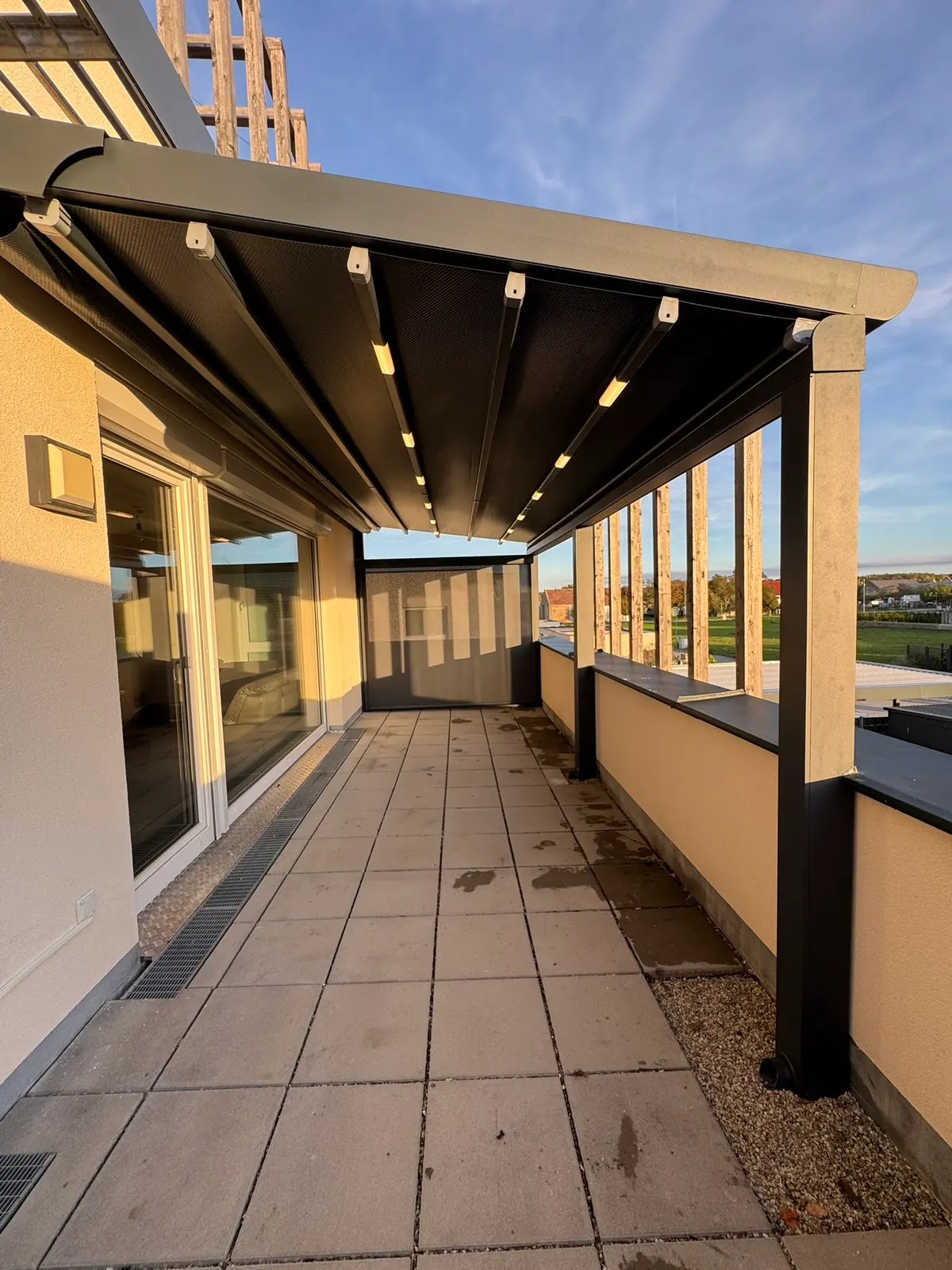 Pergola mit Faltdach entlang einer Dachterrasse, im Dach LED-Spots