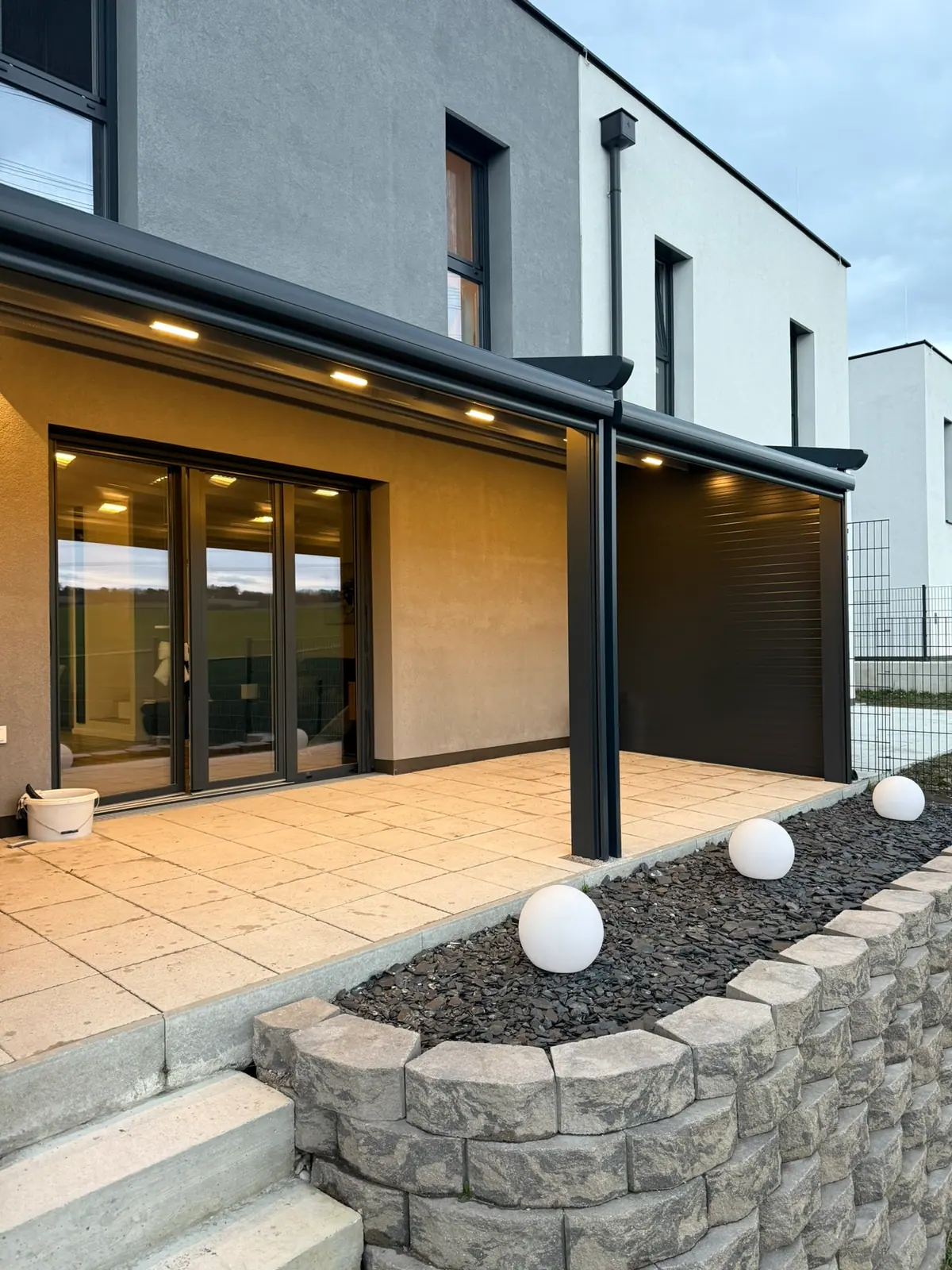Beleuchtete Faltdach-Pergola über einer Terrasse mit Stufen