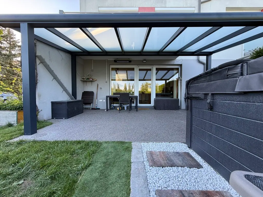 Terrasse unter einer Glasüberdachung vor einem Reihenhaus
