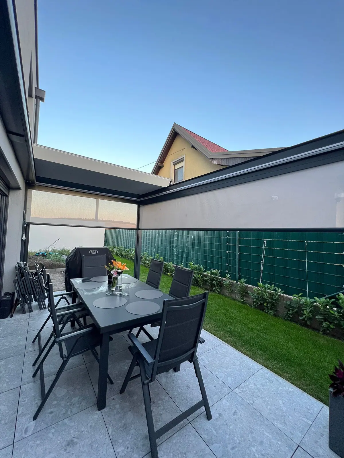 Terrasse unter einem Lamellendach mit Esstisch