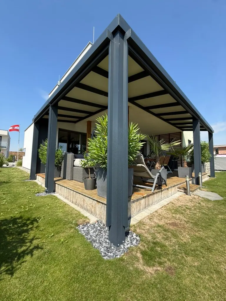 Terrassenüberdachung mit Sandwichpaneelen in Anthrazit an einem Einfamilienhaus mit Garten
