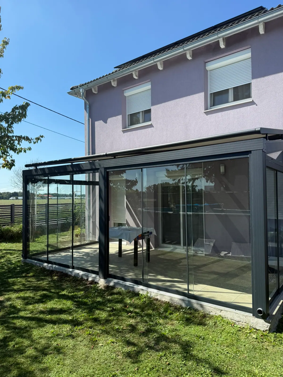 Sommergarten aus Glas mit Anthrazit-Profilen an einem Einfamilienhaus mit Garten