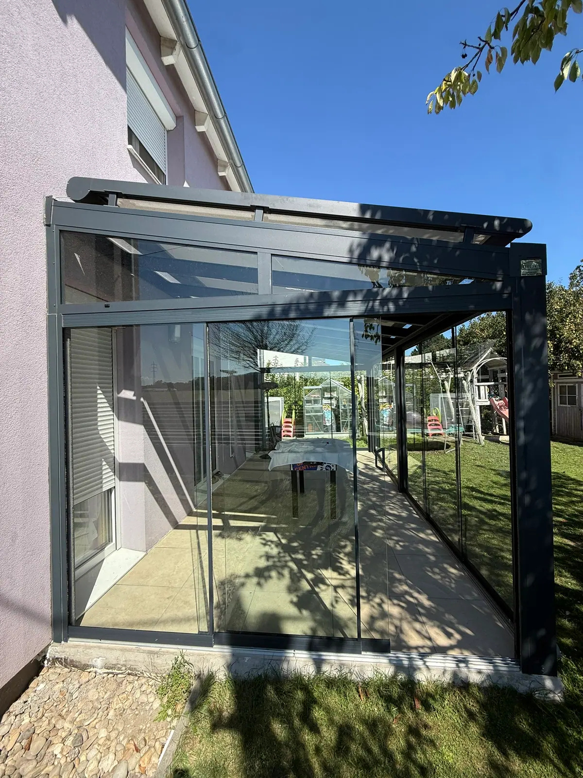 Schmaler Sommergarten aus Glas entlang einer Hauswand