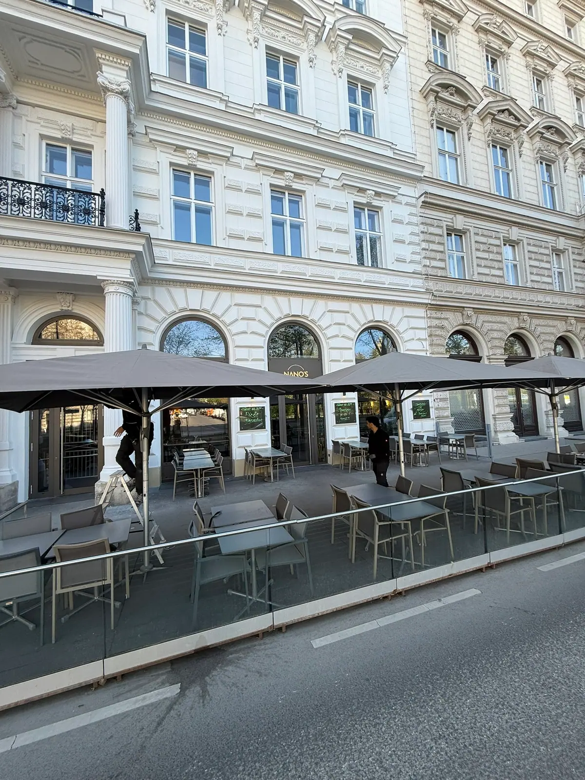 Große Sonnenschirme über einem Gastgarten vor einer Altbaufassade